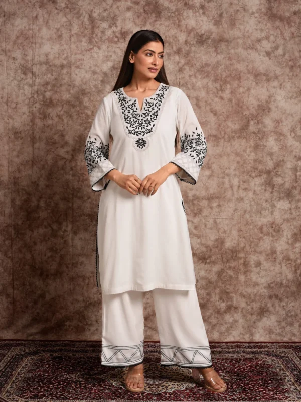 Detailed shot of black floral hand embroidery and lace trims on sleeves of Elara ivory kurta set with pants by Embrowhite