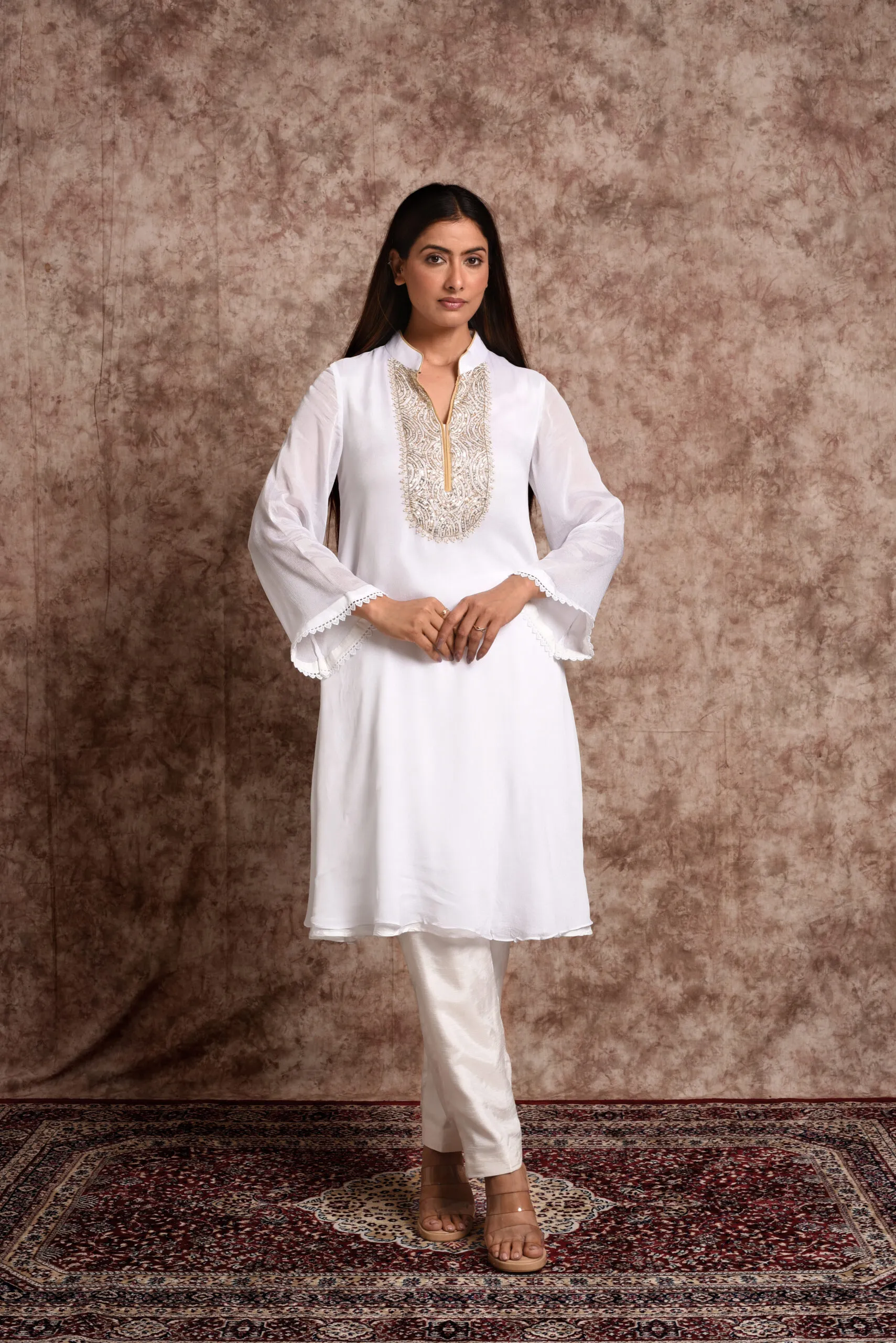 Full-length catalog view of Starlight ivory flared tunic set displaying bell sleeves and tailored straight trousers by Embrowhite Full-length catalog view of Starlight ivory flared tunic set displaying bell sleeves and tailored straight trousers by Embrowhite