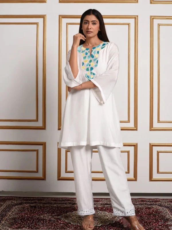 Full-length front view of Amaltas white kurta set displaying yellow and teal embroidered neckline and straight trousers with lace hem by Embrowhite