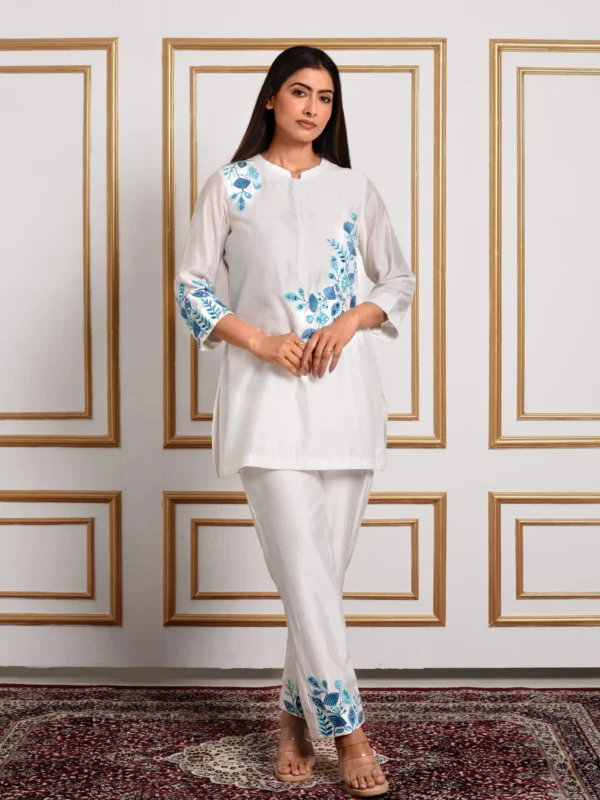 Full-length front view of Cyanne ivory 2-piece co-ord set featuring cerulean blue floral embroidery on top and trouser hems by Embrowhite