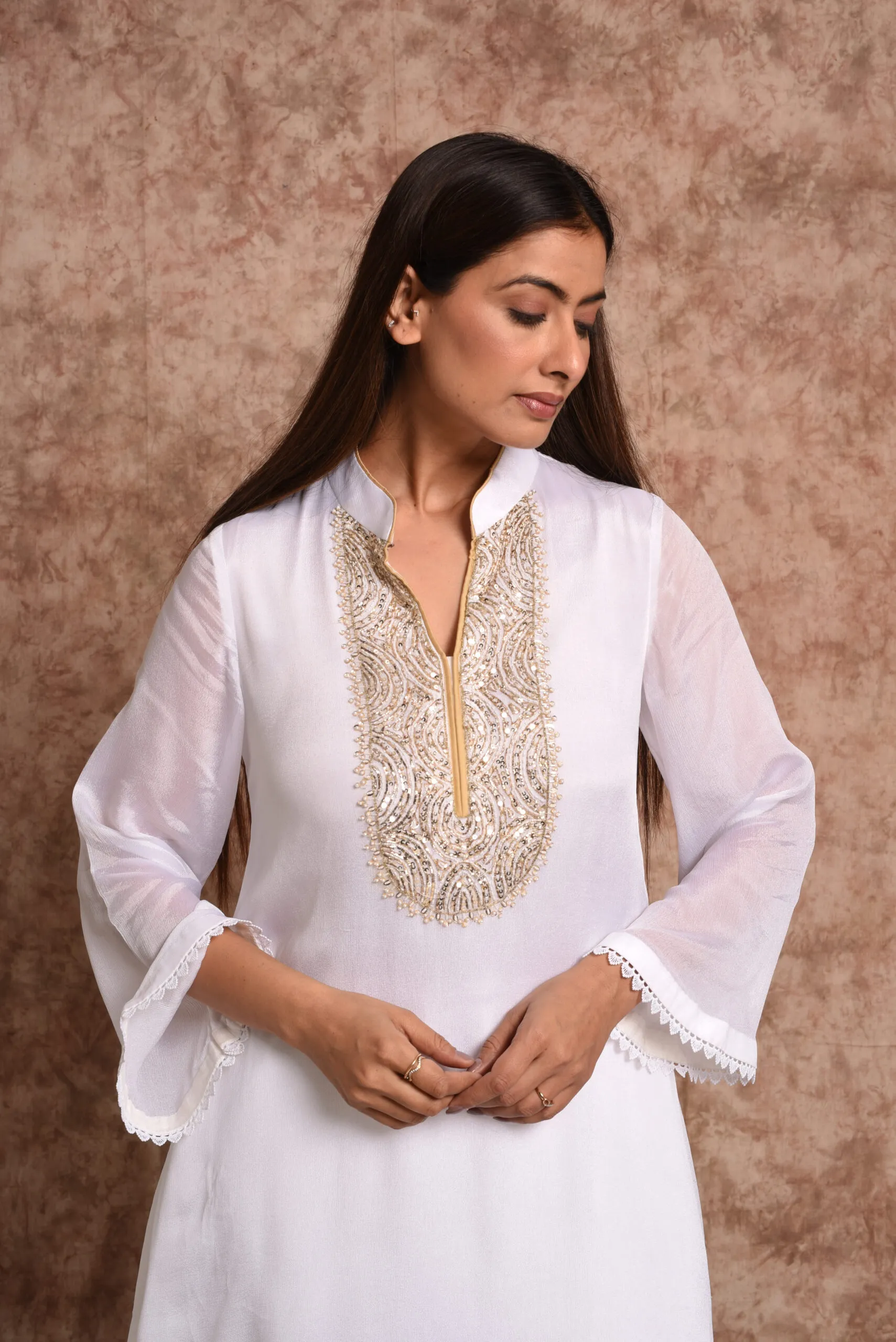 Medium close-up view of Starlight ivory kurta highlighting gold zardozi and mirrorwork bib embroidery on split neck by Embrowhite Medium close-up view of Starlight ivory kurta highlighting gold zardozi and mirrorwork bib embroidery on split neck by Embrowhite