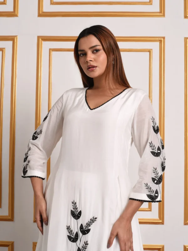 Medium side-angle view showing black leaf threadwork on sleeves and front hem of Onyx Petal monochrome set by Embrowhite
