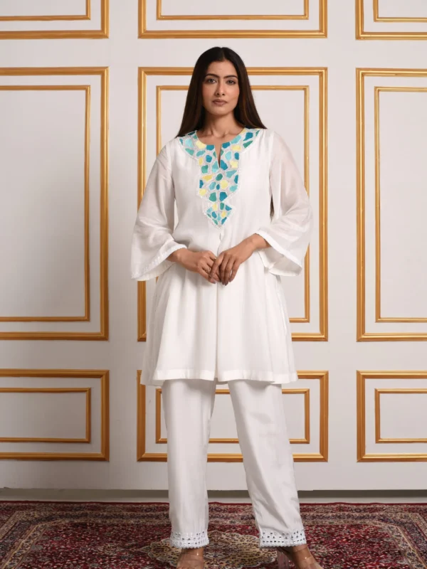 Three-quarter full-length shot of Amaltas white short kurta set with vibrant yellow mosaic applique neckline and straight pants by Embrowhite