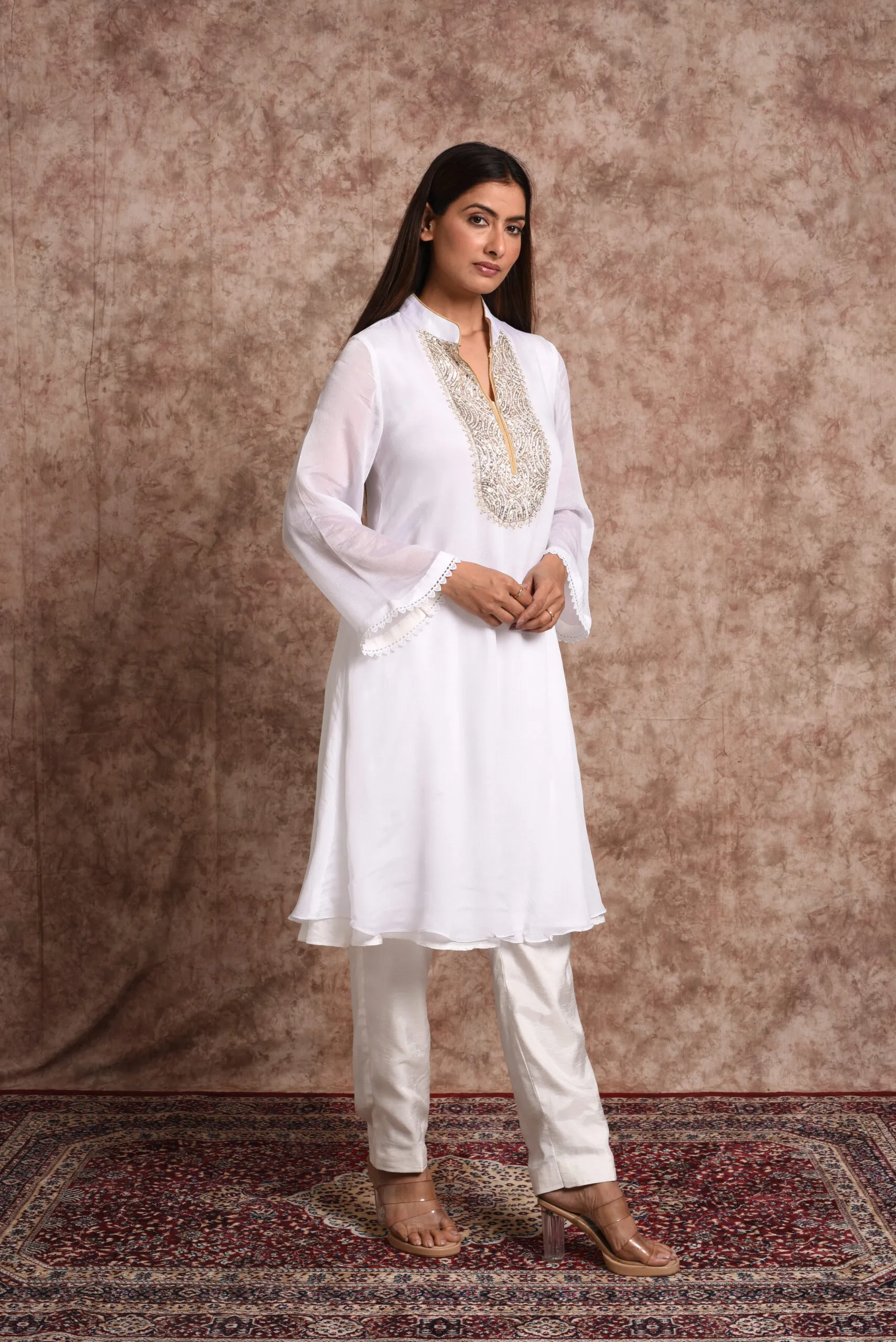 Three-quarter full-length shot of Starlight white mirrorwork kurta set showing side drape and straight-leg trousers by Embrowhite Three-quarter full-length shot of Starlight white mirrorwork kurta set showing side drape and straight-leg trousers by Embrowhite