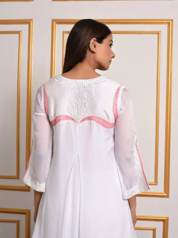 Back view close up of model wearing EmbroWhite Amara white tunic highlighting back neck embroidery and pink yoke accents