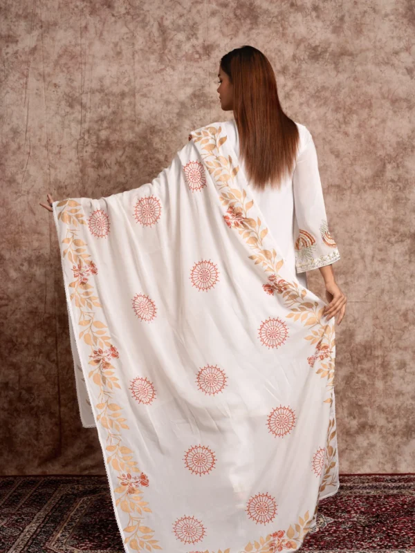 Back view of model holding out white printed dupatta with terracotta motif border from EmbroWhite Zaira set