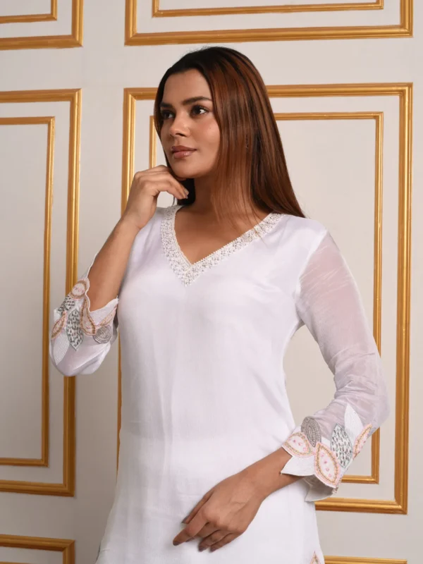 Close up shot of model highlighting pearl beaded V-neckline and vine embroidered cuffs on EmbroWhite Aquila tunic