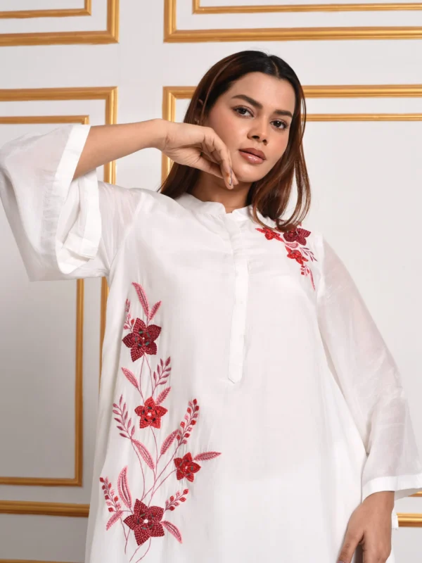 Close up shot of model posing in EmbroWhite Amara white tunic showing detailed red and pink floral threadwork