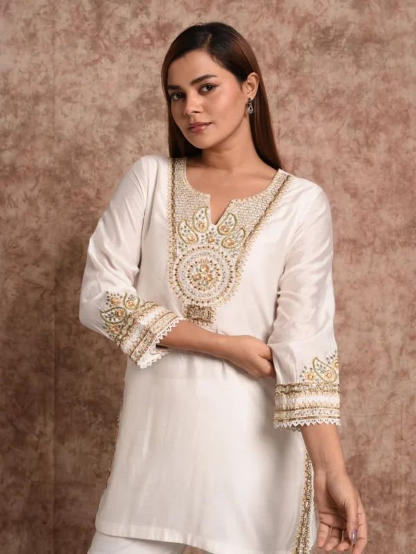 Close-up view of intricate gold hand-embroidered neckline yoke and sleeve borders on Sage Radiance short tunic by Embrowhite