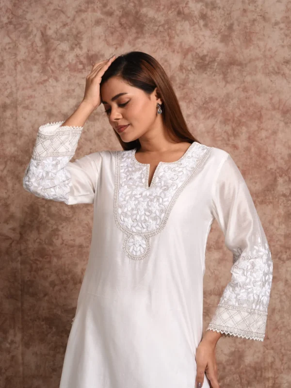 Close-up view of intricate white floral chikankari embroidery on neckline of Kaira white tunic by Embrowhite