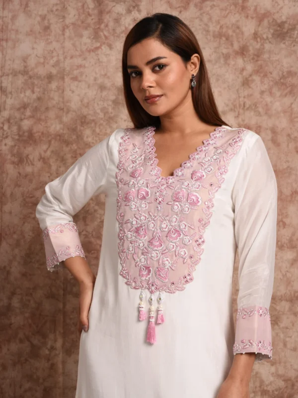 Close-up view of pink floral threadwork yoke, tasselled neck detail, and scalloped V-neckline on Inara off-white tunic by Embrowhite