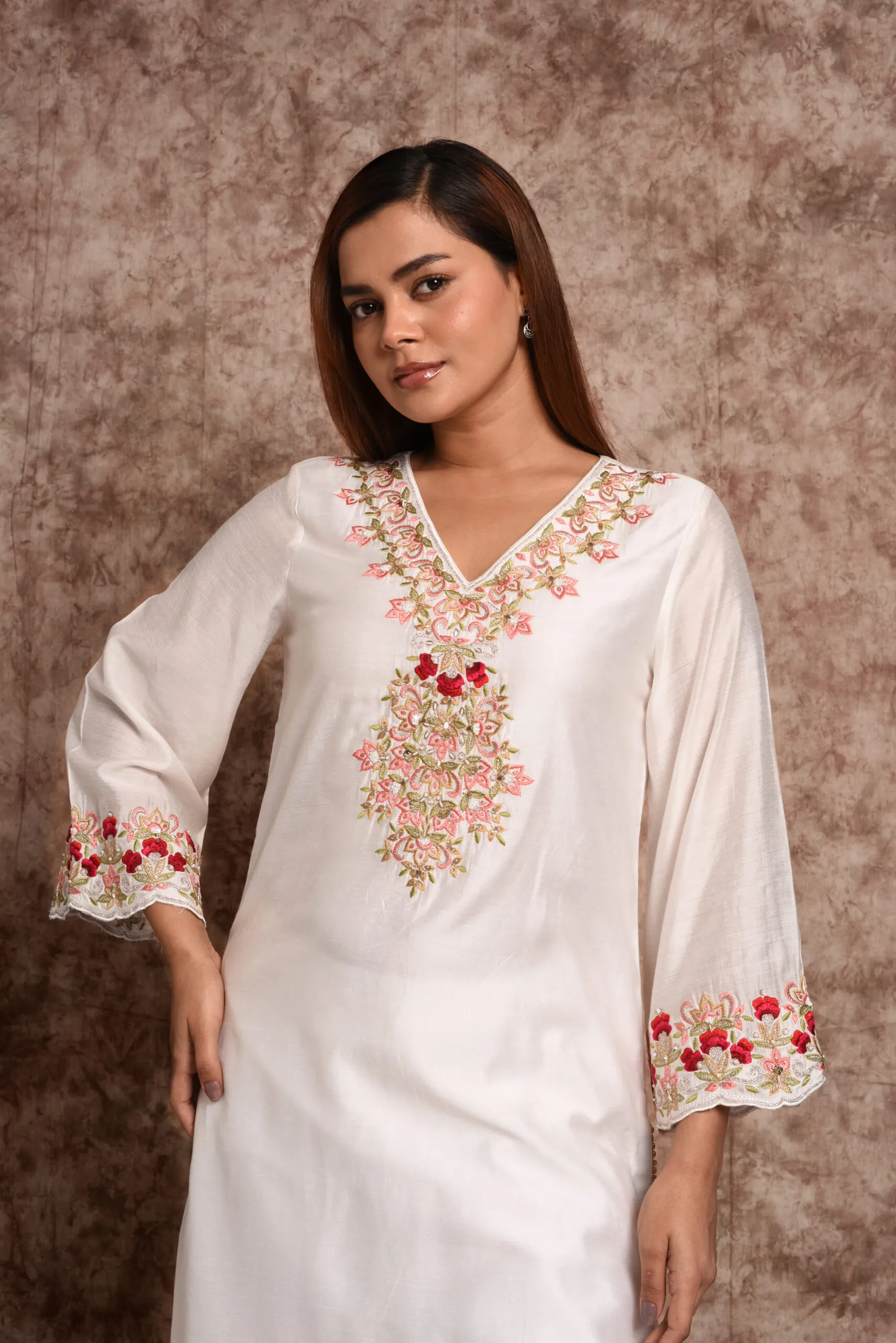 Front view pose of model in EmbroWhite Zoya white tunic kurta featuring pink and red botanical neck embroidery Front view pose of model in EmbroWhite Zoya white tunic kurta featuring pink and red botanical neck embroidery