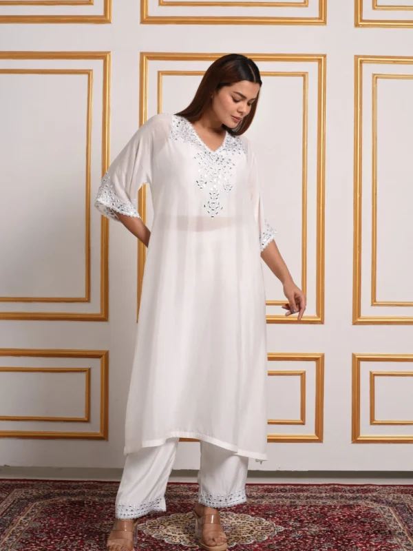 Full-length front view of model in Sage Radiance white kaftan kurta set with silver mirror embellishments and straight trousers by Embrowhite