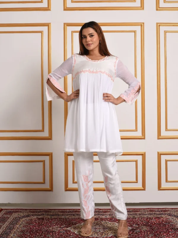 Full length view of model standing in EmbroWhite Inara ivory scalloped co-ord set and pink embroidered trousers