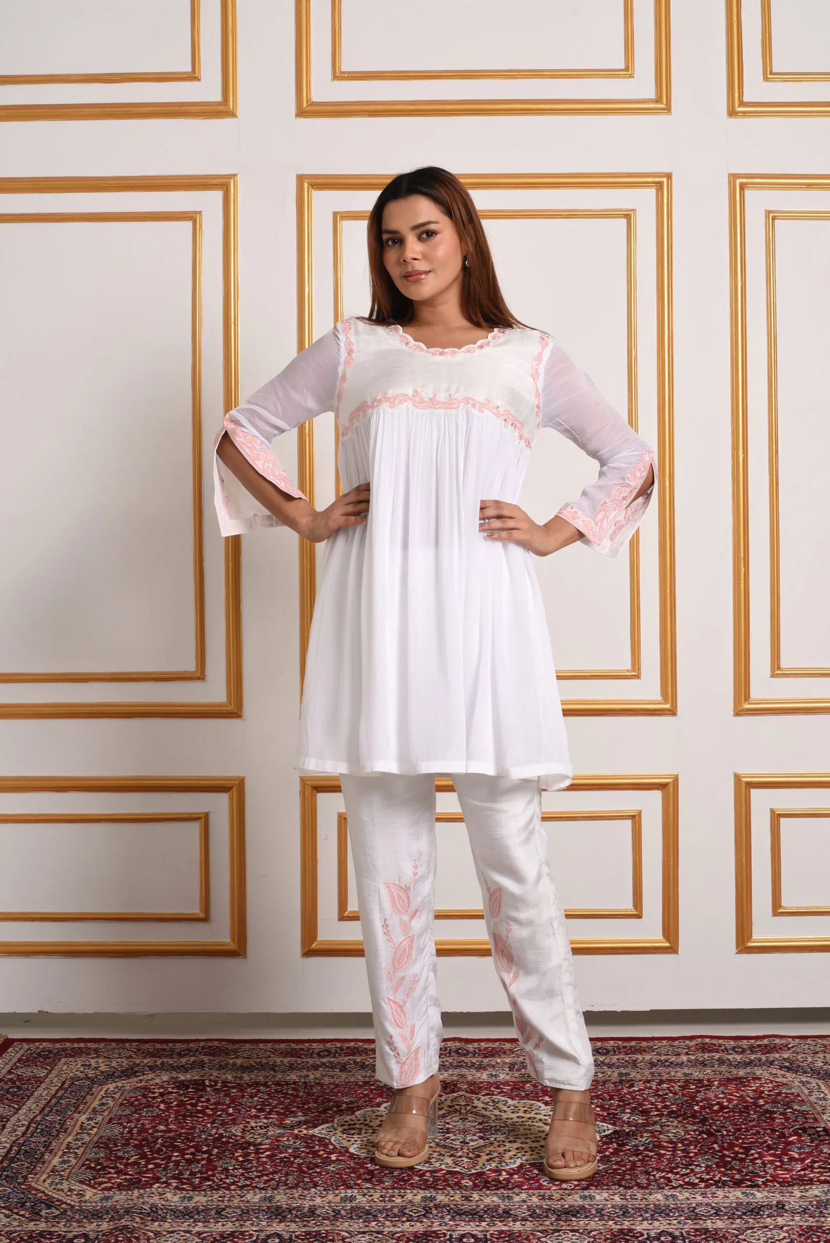Full length view of model standing in EmbroWhite Inara ivory scalloped co-ord set and pink embroidered trousers Full length view of model standing in EmbroWhite Inara ivory scalloped co-ord set and pink embroidered trousers