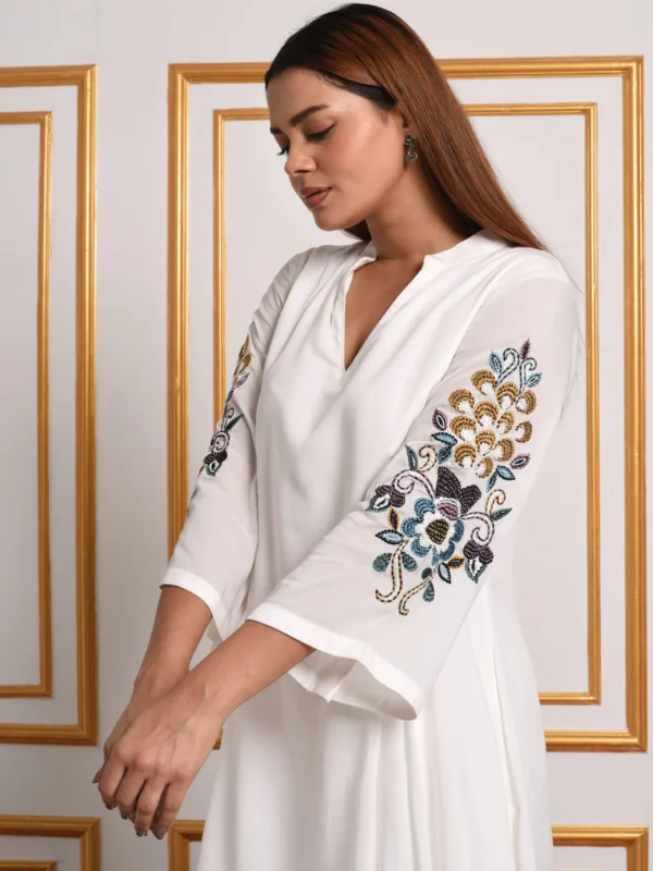 Medium shot of Liana off-white co-ord top displaying intricate floral swirl embroidery on flared sleeves by Embrowhite