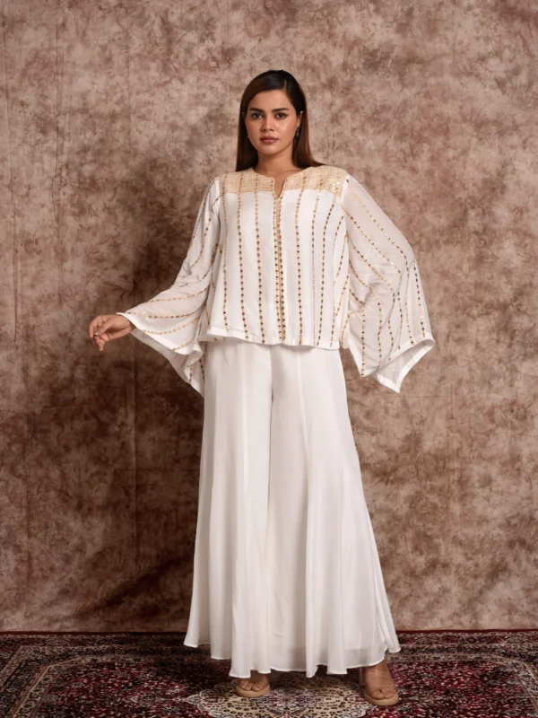 Model posing in EmbroWhite white embellished kaftan top and wide-leg palazzo pants